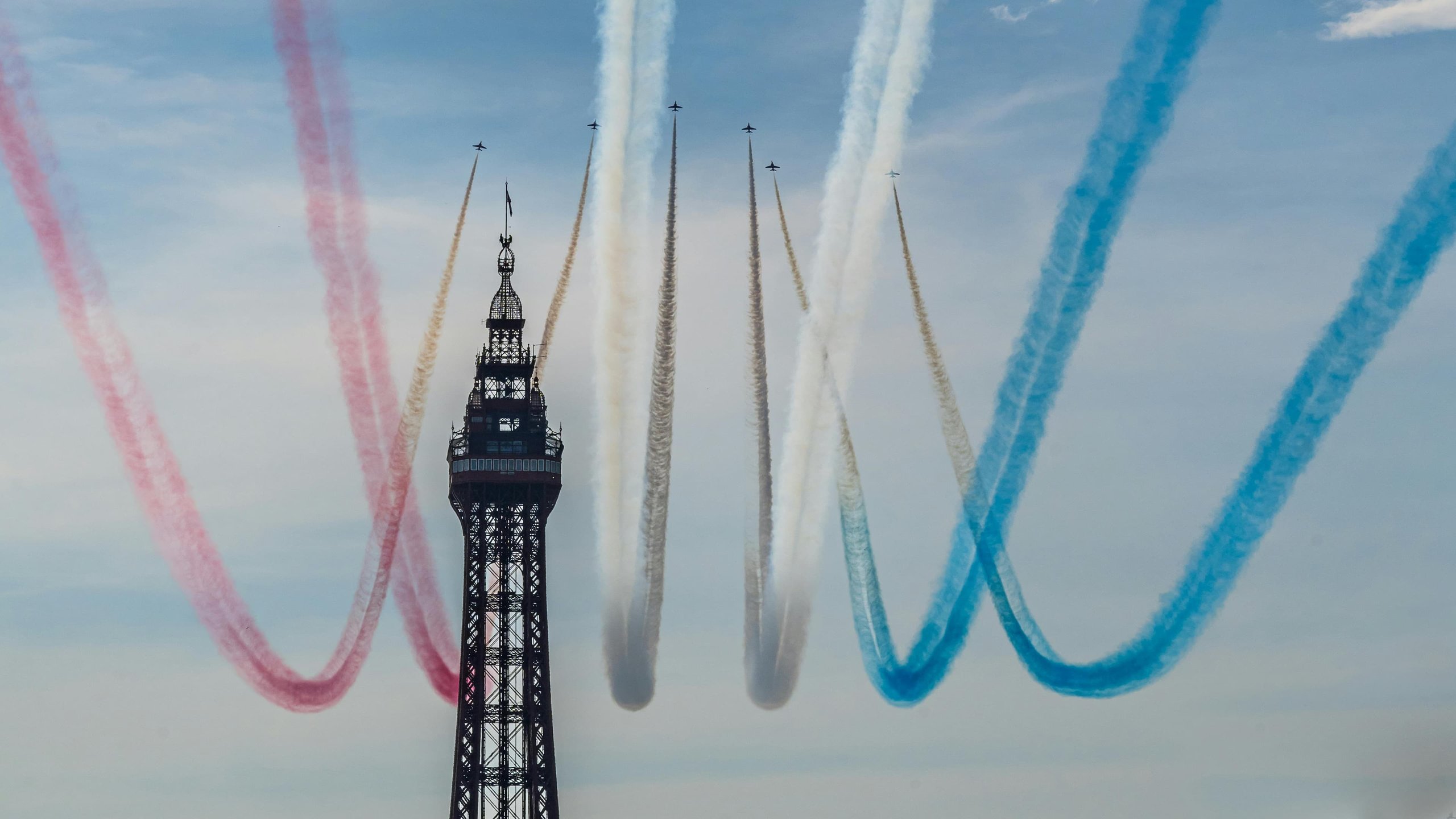 Aerobatic planes with colored smoke trails in sky. Blackpool Tower.