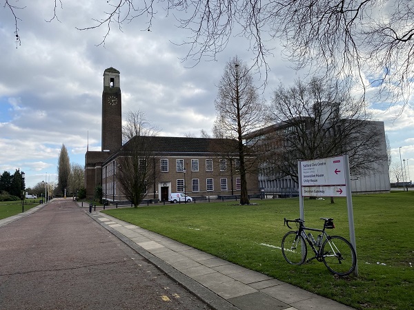 Building with clock tower, bike, sign, and path.