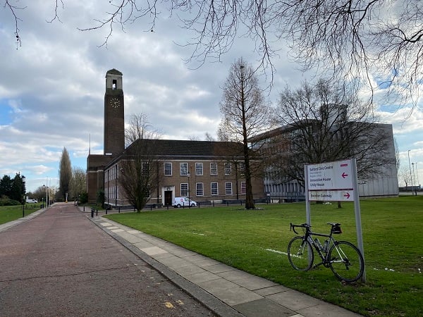 Building with clock tower, bike, sign, and path.