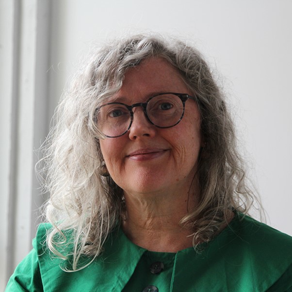 Woman with glasses and gray hair, green top.
