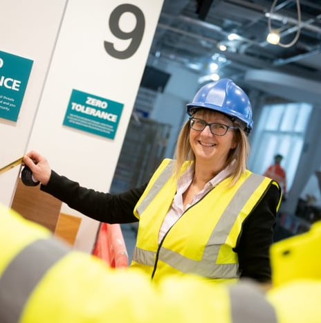 Two construction workers measuring with a tape measure. One is smiling.