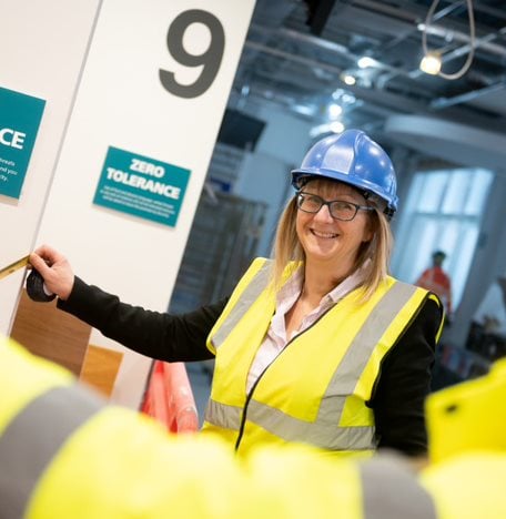 Two construction workers measuring with a tape measure. One is smiling.
