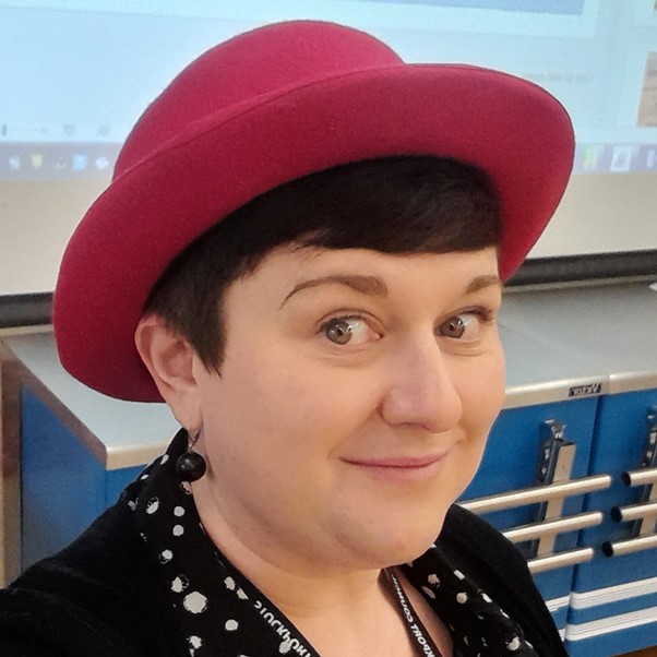 Woman with hat and black polka dot top looking at the camera.