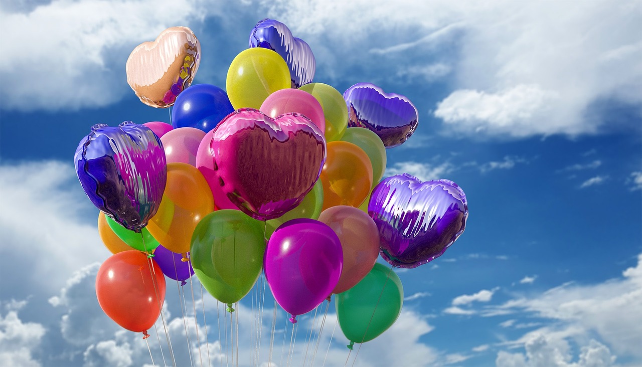 Colorful balloons against a blue sky with clouds.
