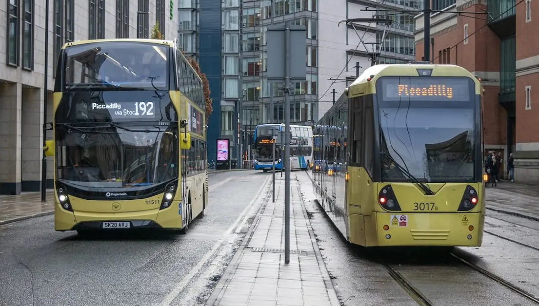 Yellow bus and tram in a city with buildings.