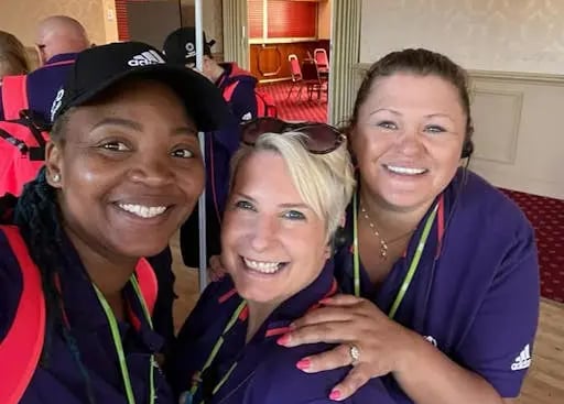 Three women posing for photo, smiling, wearing matching attire.