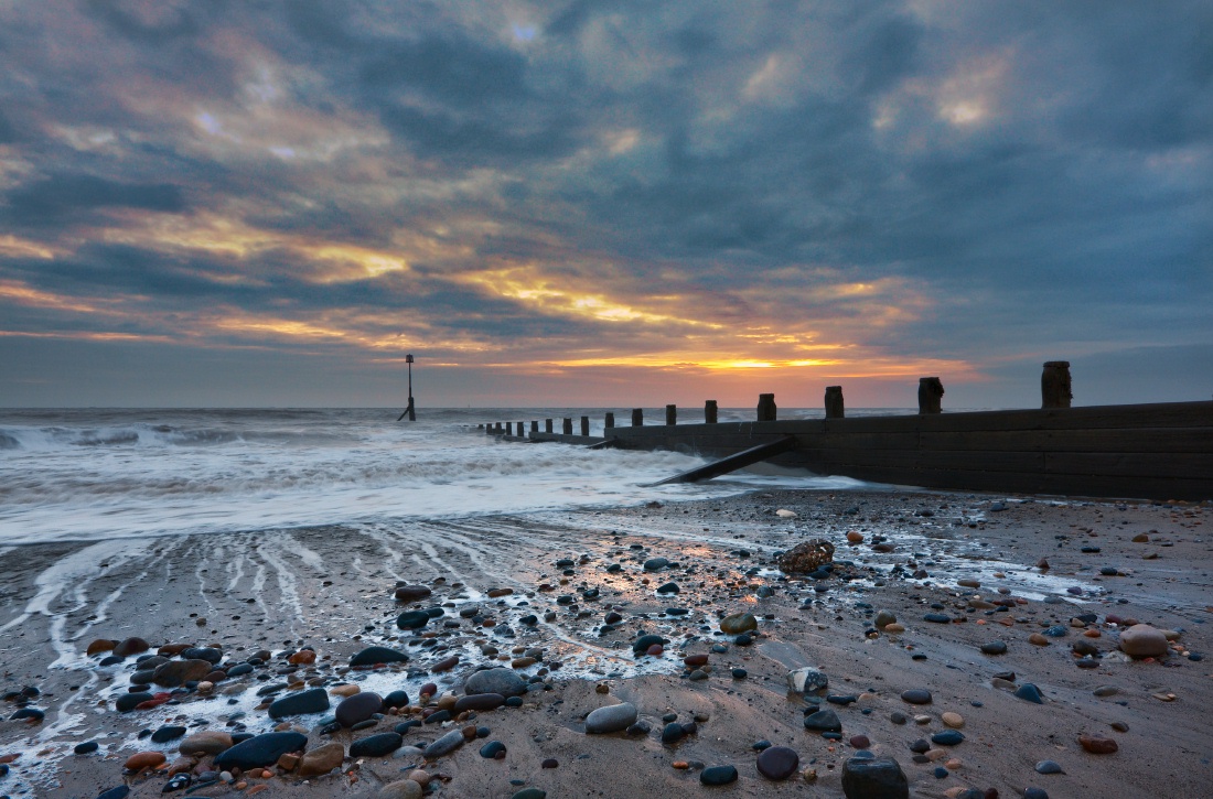 Dawn at Hornsea beach with a wooden barrier and cloudy sky.