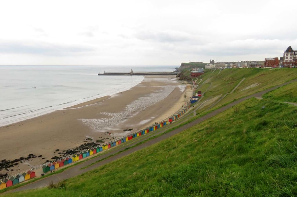 View of beach and colorful beach huts on a hillside.