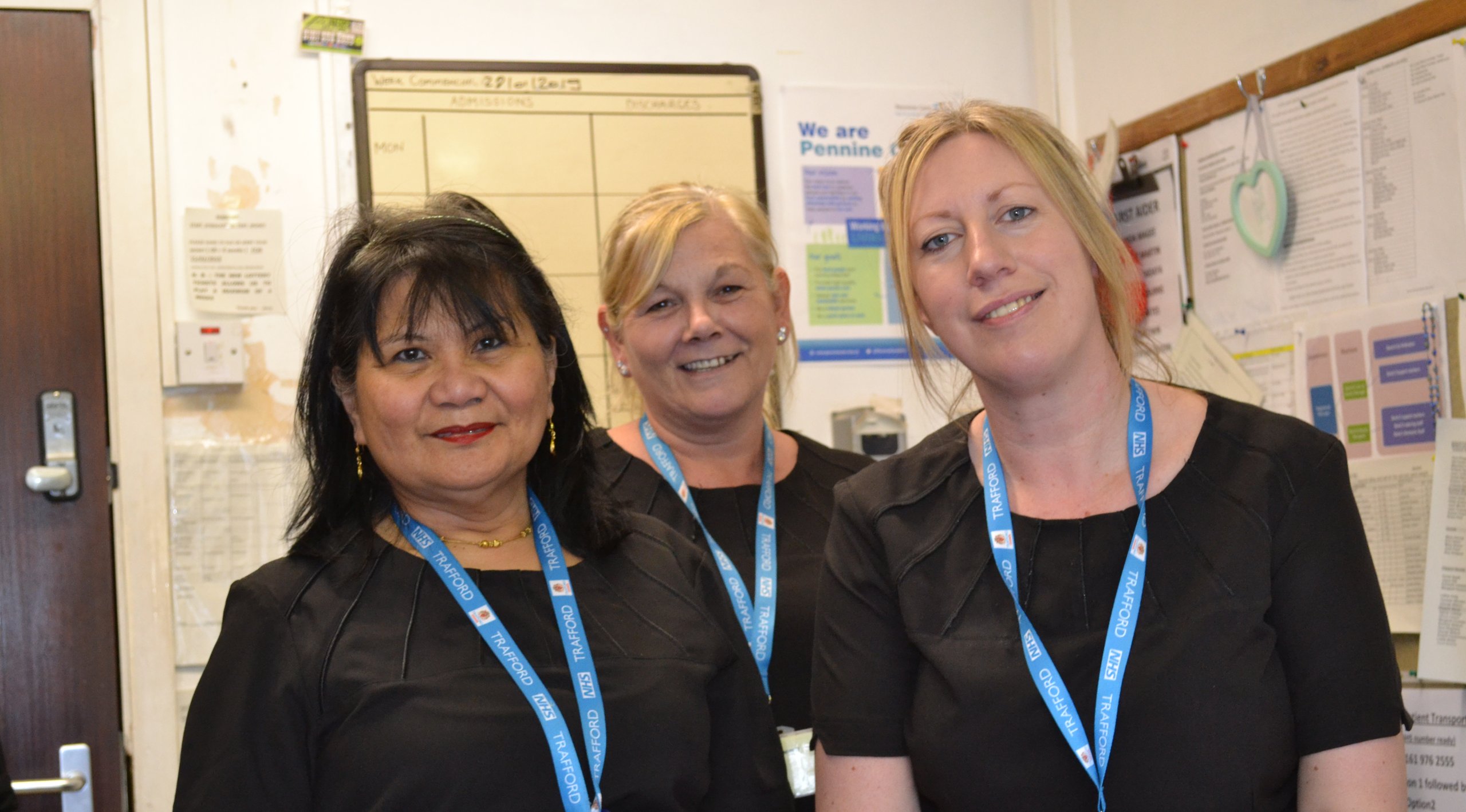 Three women wearing name badges, posing in front of a wall.
