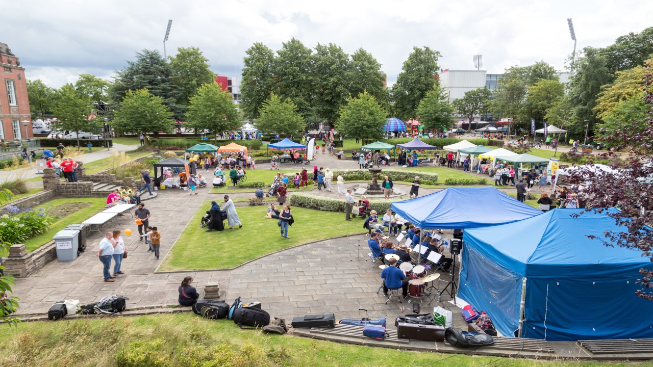 People gathered in park with tents and band.