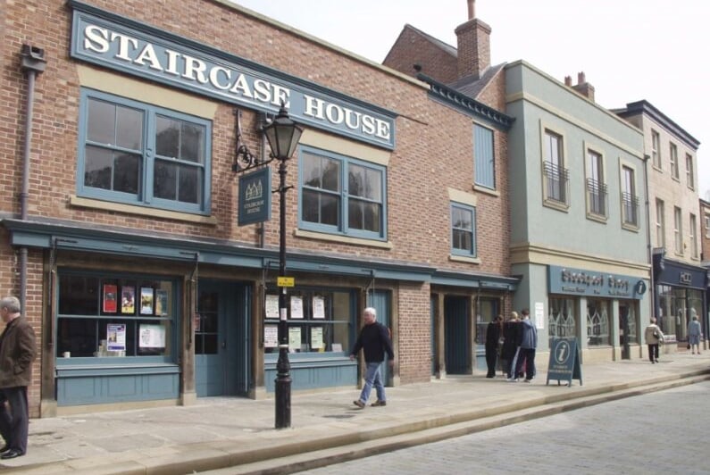 Buildings with signs and storefronts on a brick street.