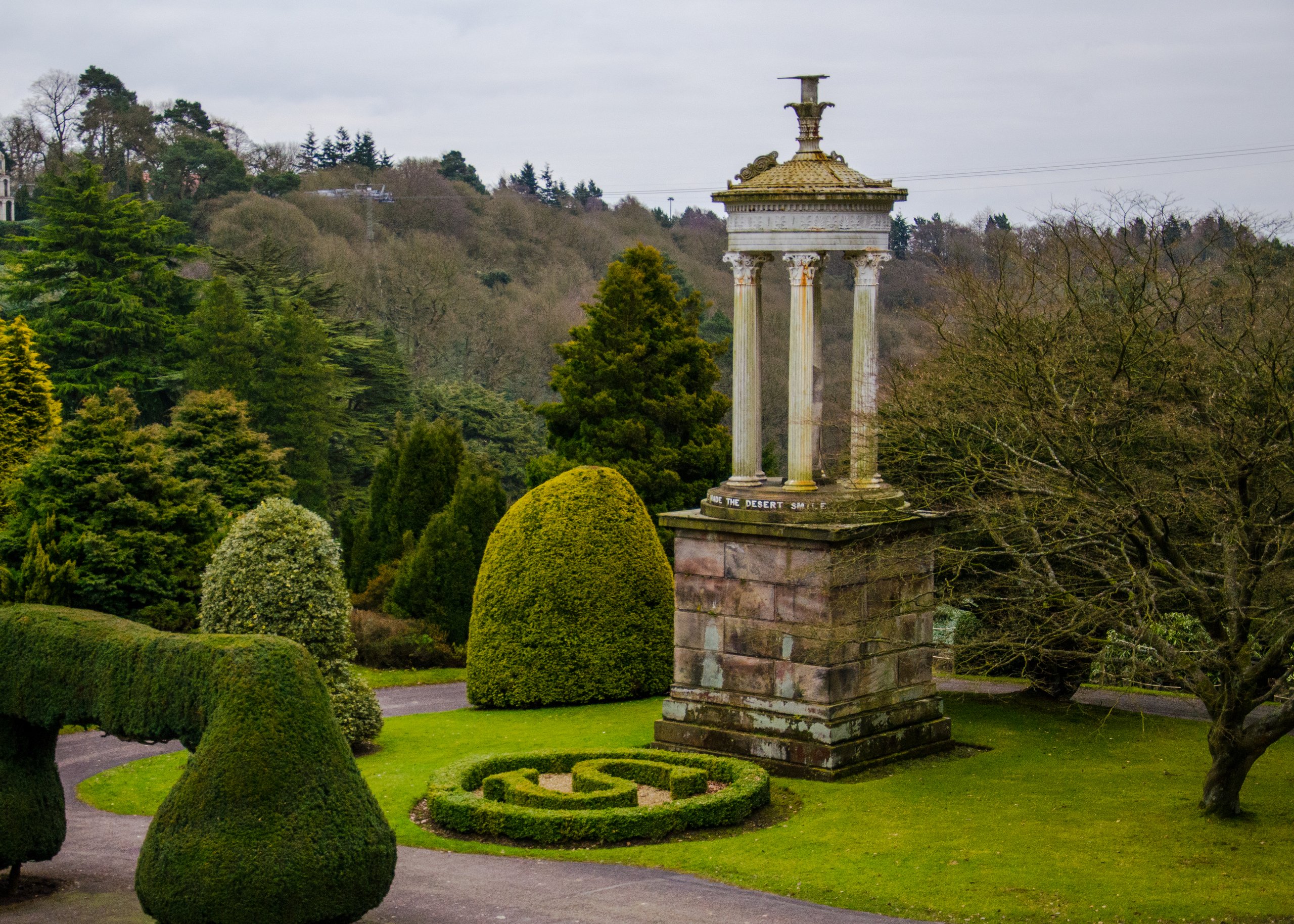 Ornamental gardens with trees, paths, sculptures, and architectural details.