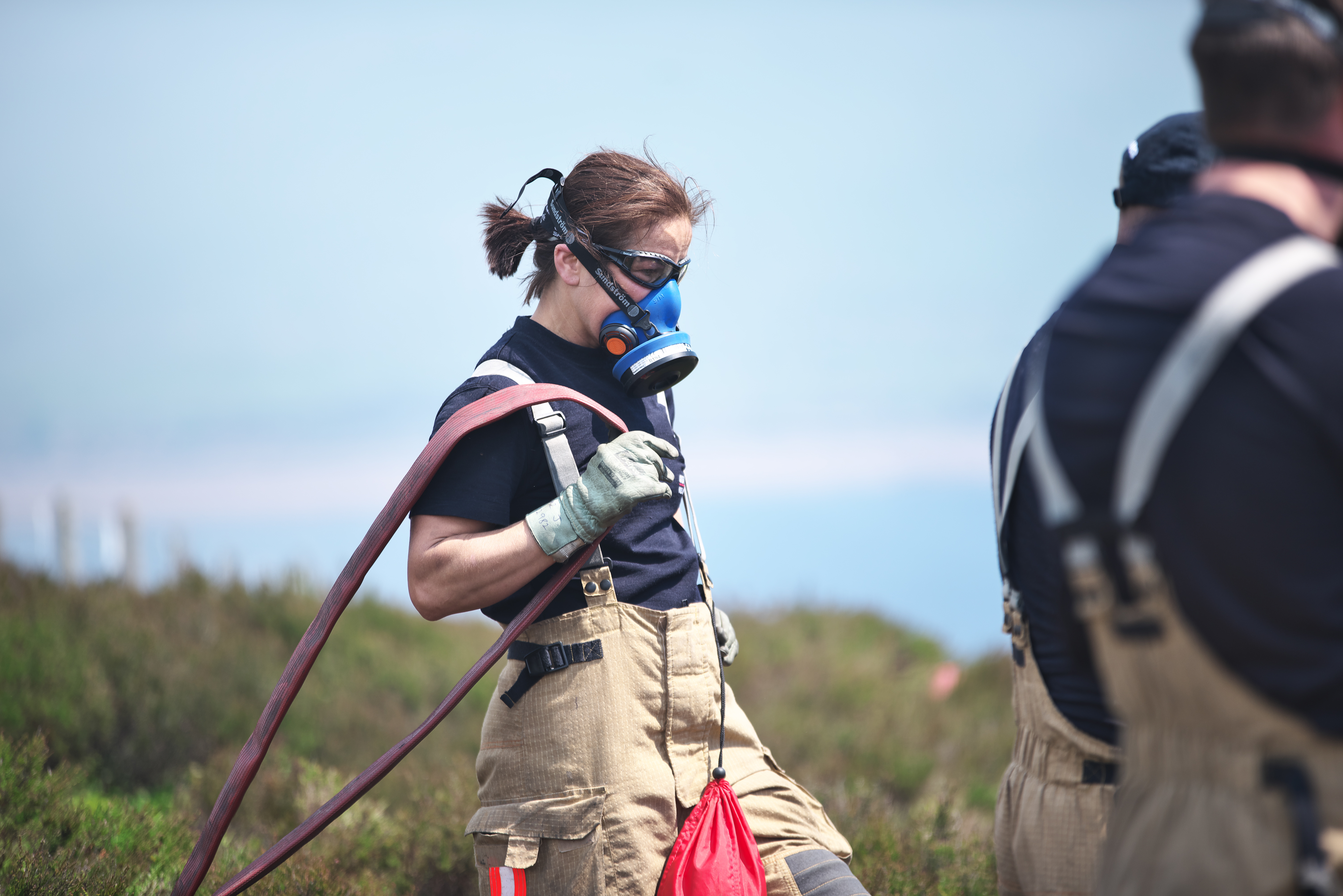 Firefighter wearing a respirator with a hose.