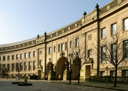 Curved stone building with arches, windows, and trees.