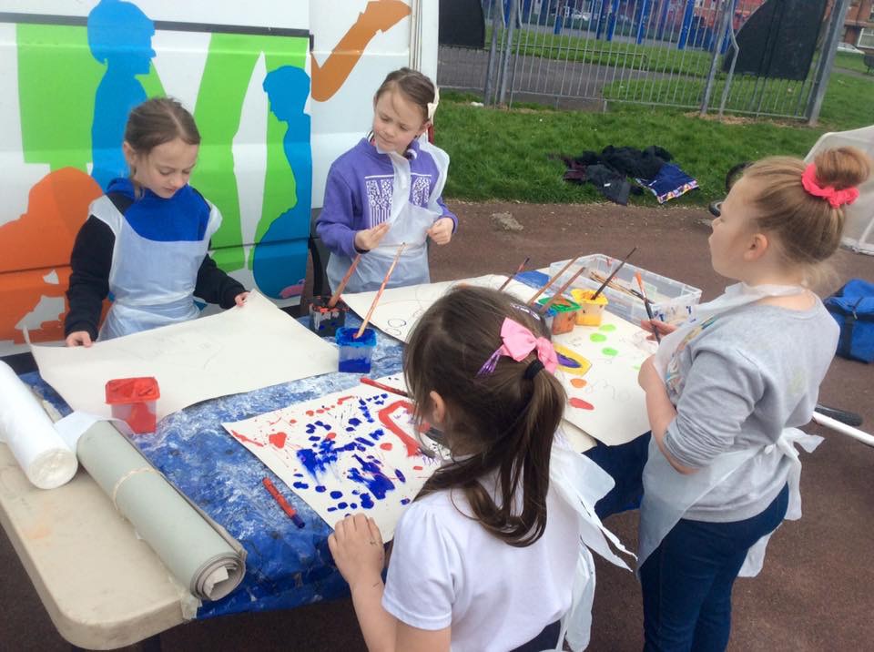 Kids with paint and brushes working on art projects.