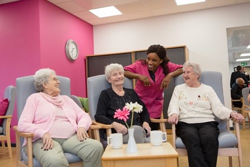 Care home staff with residents smiling and laughing.