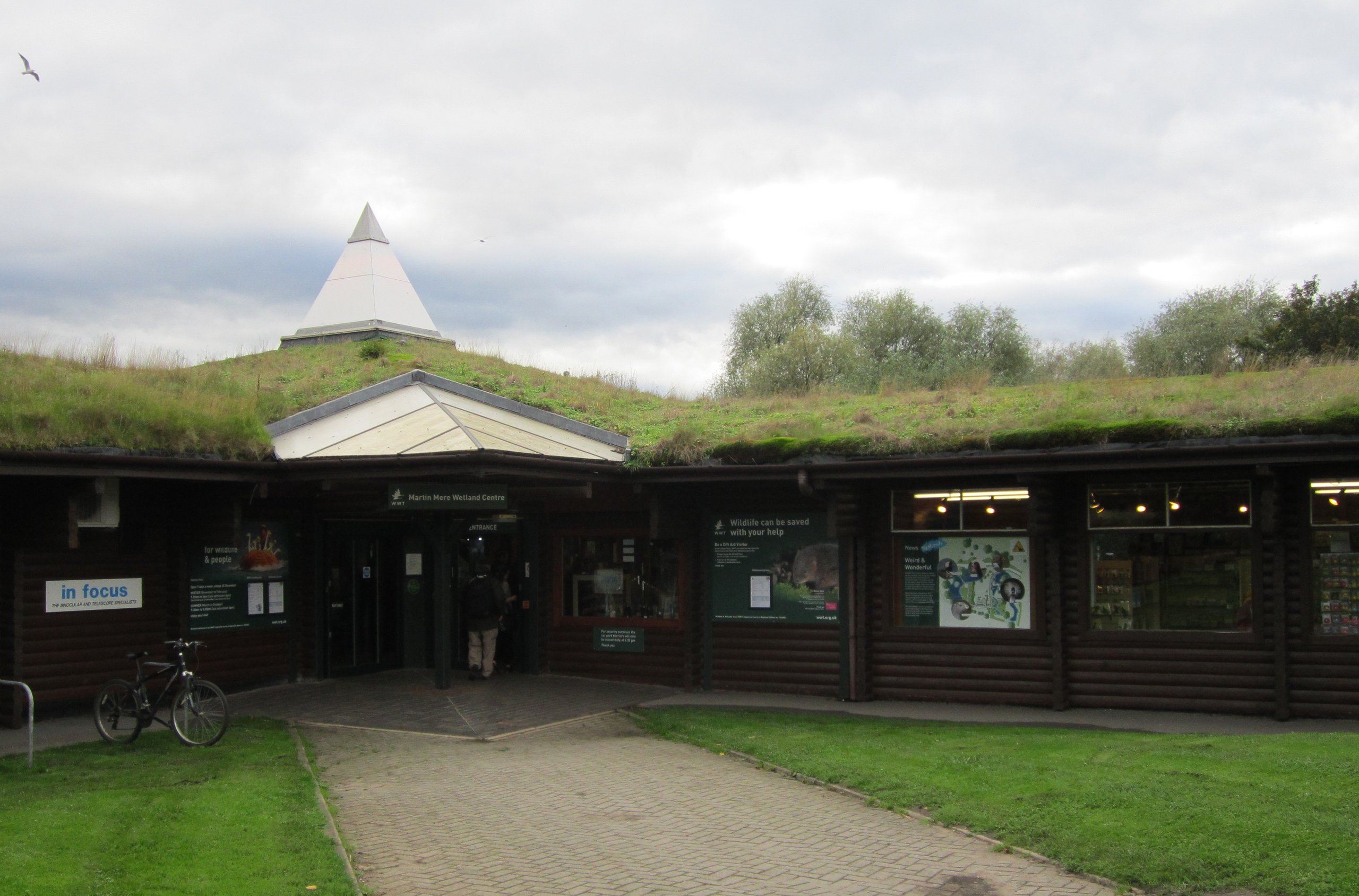 Exterior of Martin Mere Wetland Centre entrance. Buildings with grass roofs and a stone path.