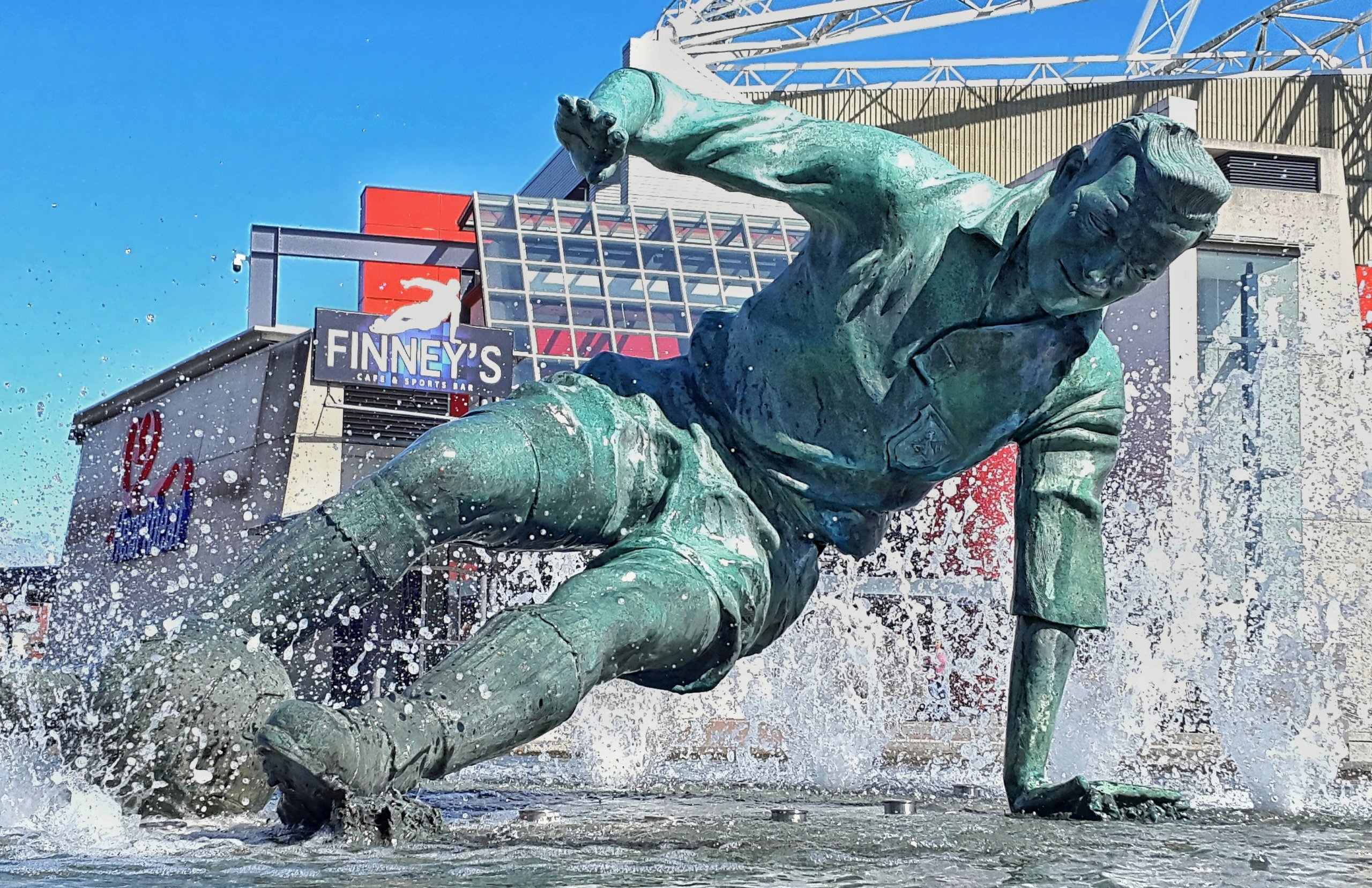 Bronze statue of Tom Finney in water fountain, splashing.