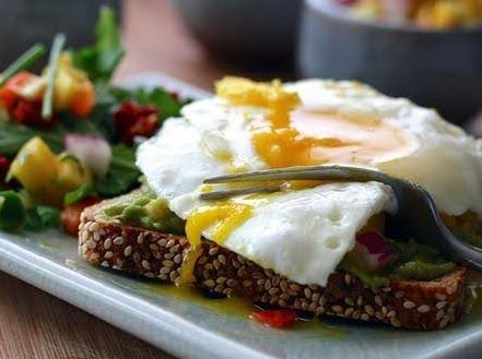 Toast with egg and salad on a plate.