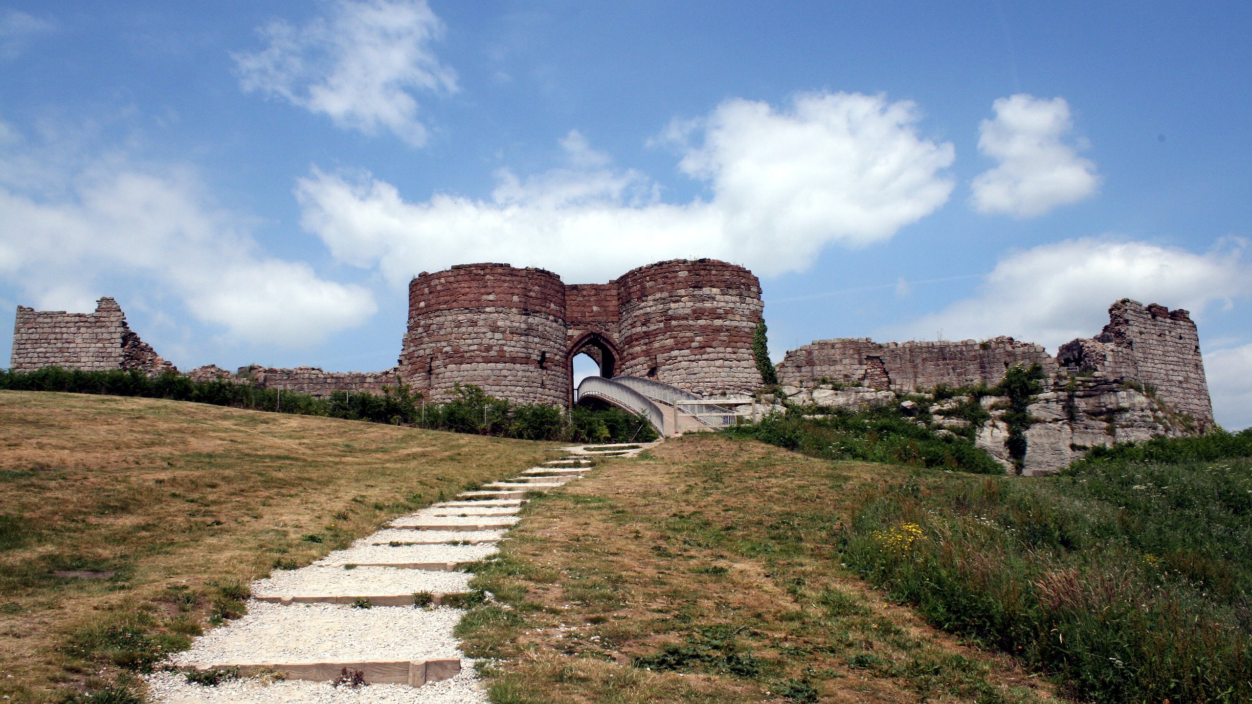 Stone castle ruins with a blue sky and clouds.