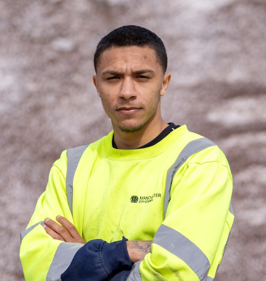 Man wearing a high visibility jacket, Manchester City Council logo.