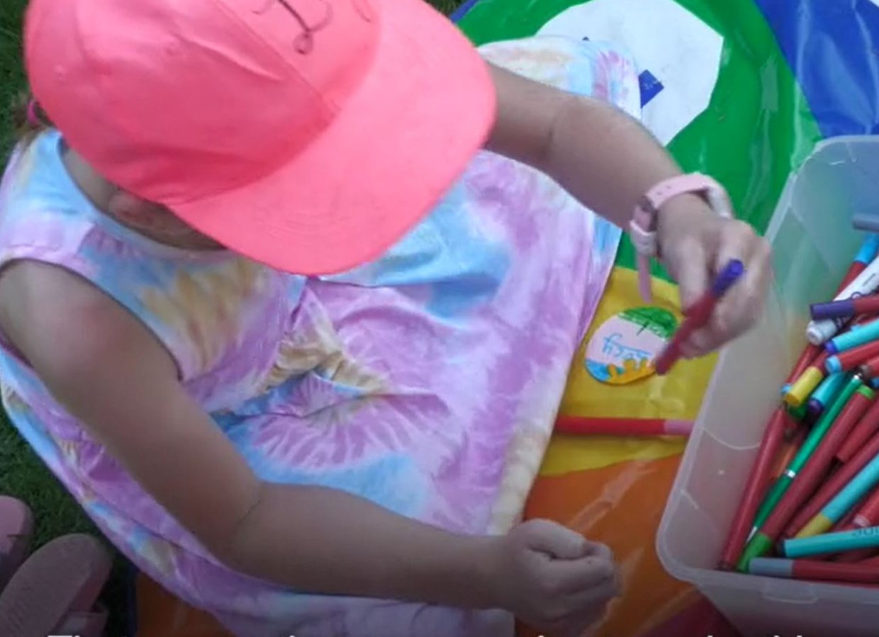 Girl in pink hat coloring with markers.