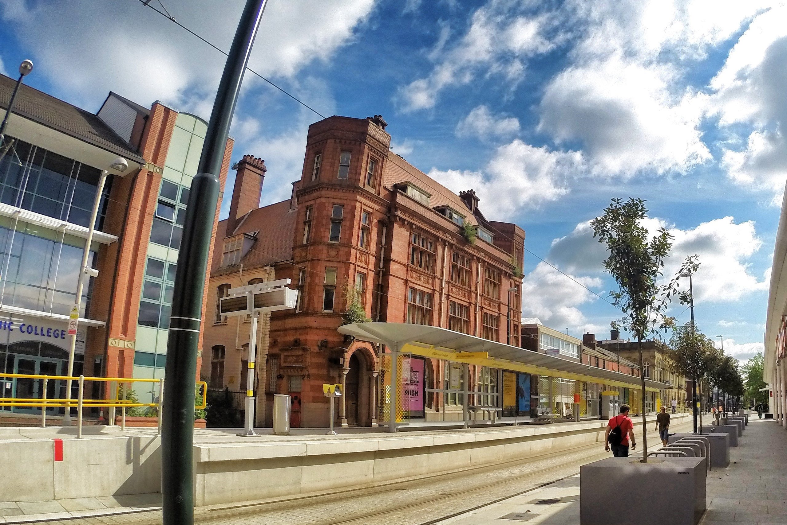 Buildings, train tracks, and pedestrians on a sunny day.