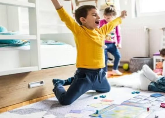 Boy celebrating a win while playing board games with family.