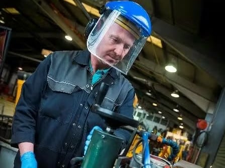 Mechanic wearing safety gear working with a grinding tool.