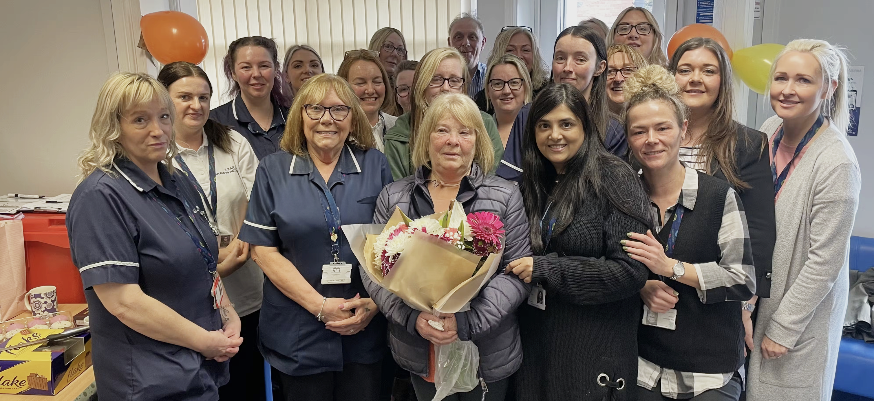 Group of people smiling, holding flowers.