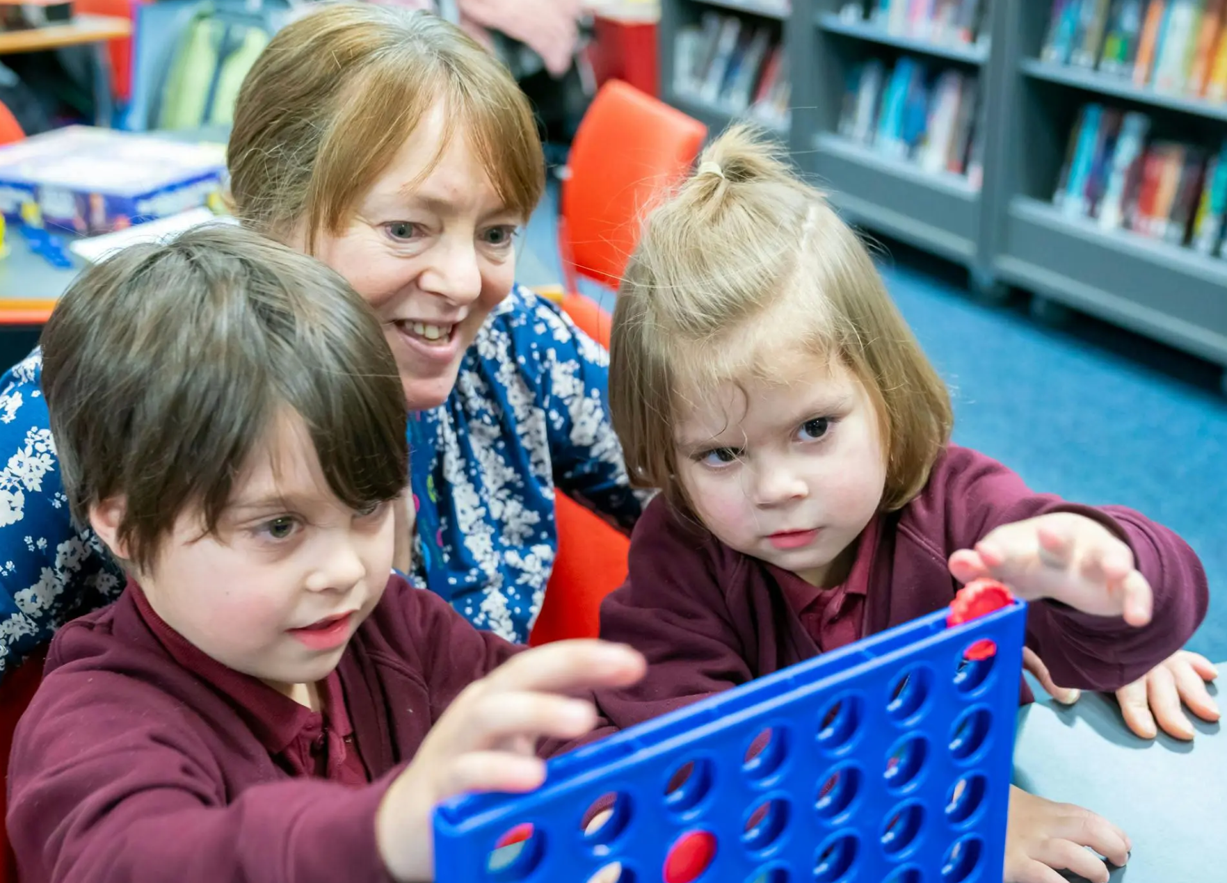 A woman and two kids playing a game together.