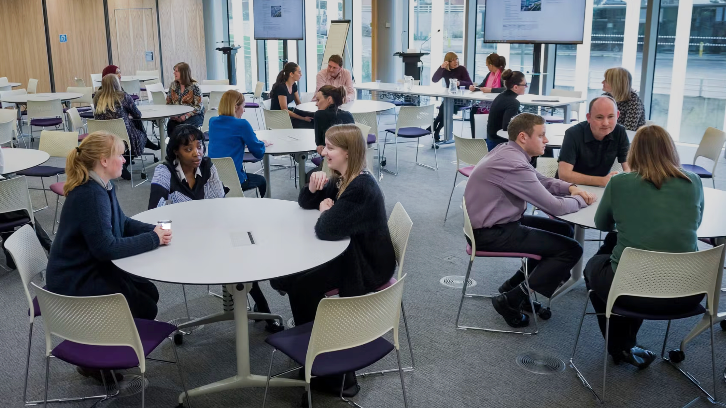 People sitting at tables in a modern meeting room.