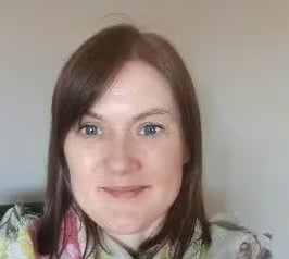 Woman with brown hair and blue eyes wearing a floral scarf.