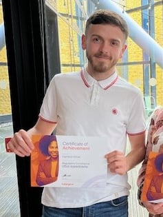 Two graduates holding certificates.