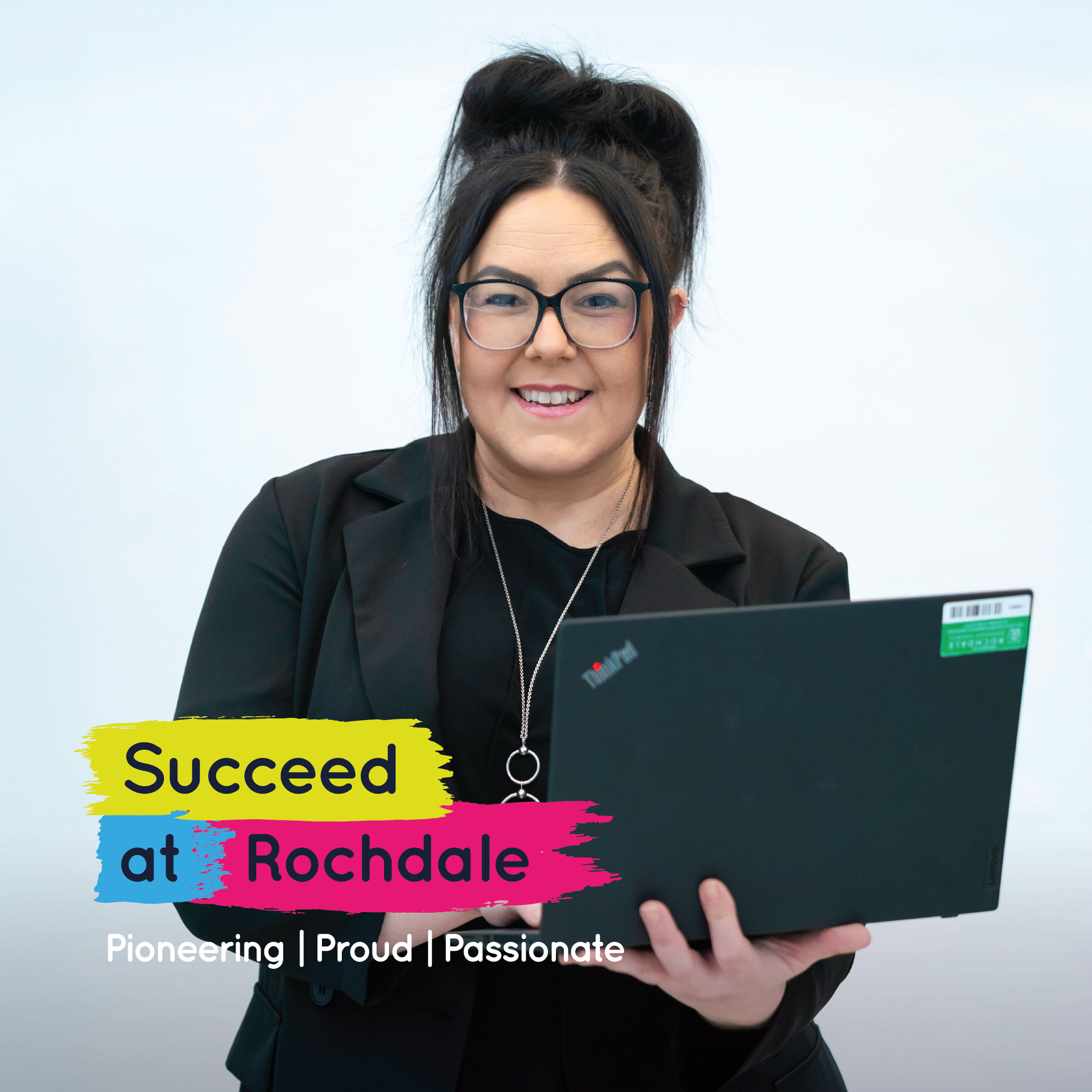 A woman with glasses and her hair in a bun smiles while holding a laptop. Text reads "Succeed at Rochdale" and "Pioneering