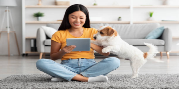Picture of a woman sat on the floor with her dog on an i-pad